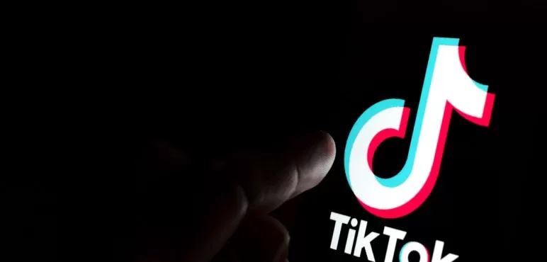 Kırmızı zemin üzerinde video oynatma simgeli telefon, TikTok işareti ve hashtag sembolleri içeren illüstrasyon.