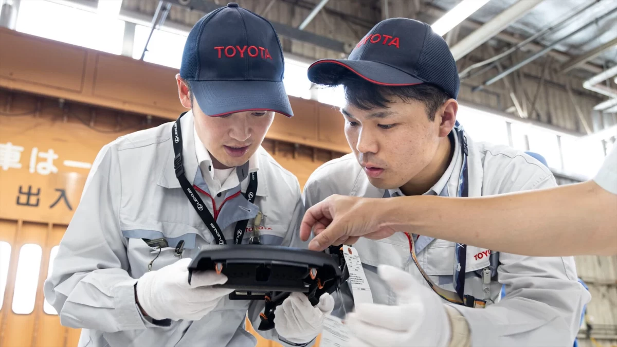 Toyota çalışanları bir otomobil parçasını inceliyor