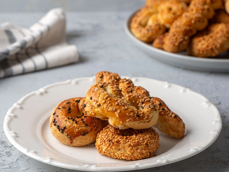 Beyaz tabakta üst üste dizilmiş susamlı ve çörek otlu kurabiyeler