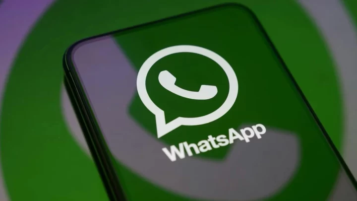 Yeşil zemin önünde ekranda WhatsApp logosu bulunan bir akıllı telefon