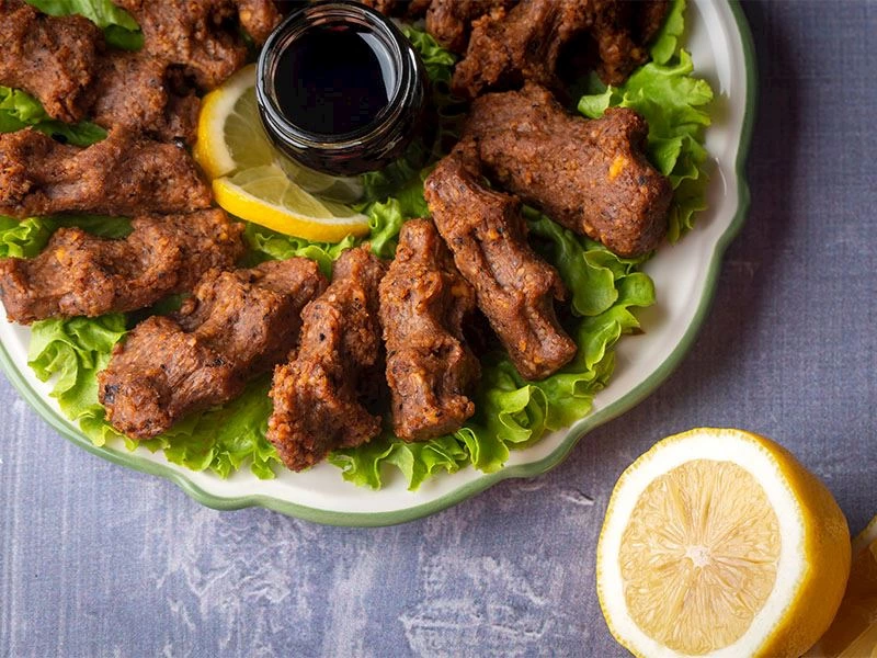 Tabakta çiğ köfte, yeşillikler, limon ve sos