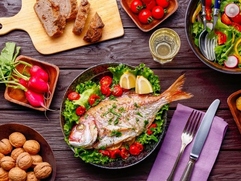 Yeşillik ve limonla servis edilen ızgara balık