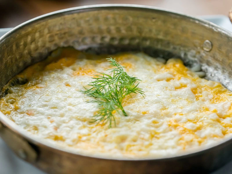 Tavada pişmiş yumurta ve erimiş peynirin üzerinde dereotu