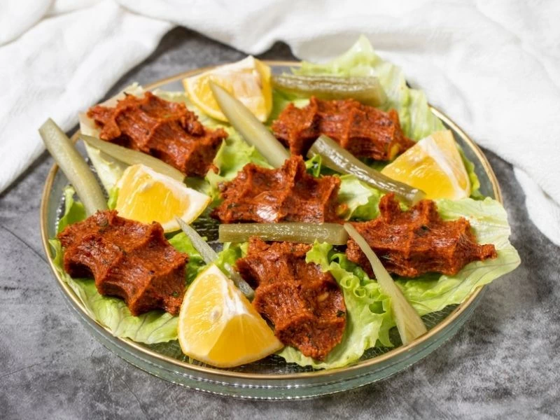 Marul ve limon dilimleriyle servis edilen yumurtalı çiğ köfte