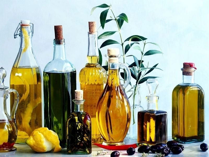 Farklı biçimlerdeki şişelerde zeytinyağı, zeytin ve limonlar